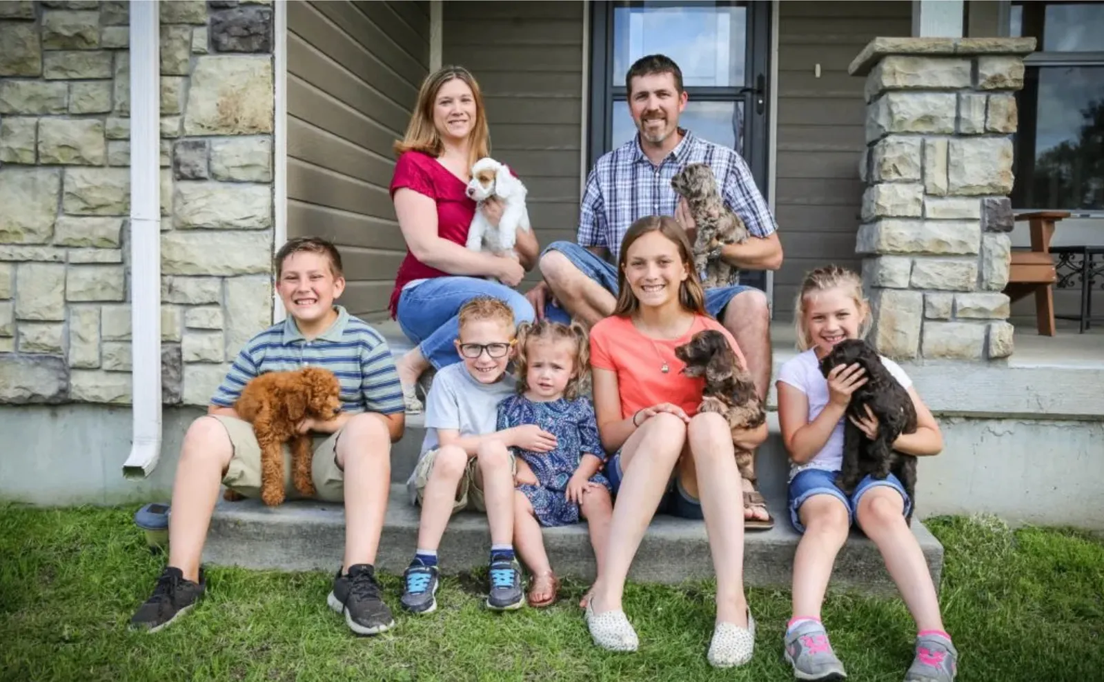 The Mueller family with their seven children and Australian Labradoodle puppies on the front porch